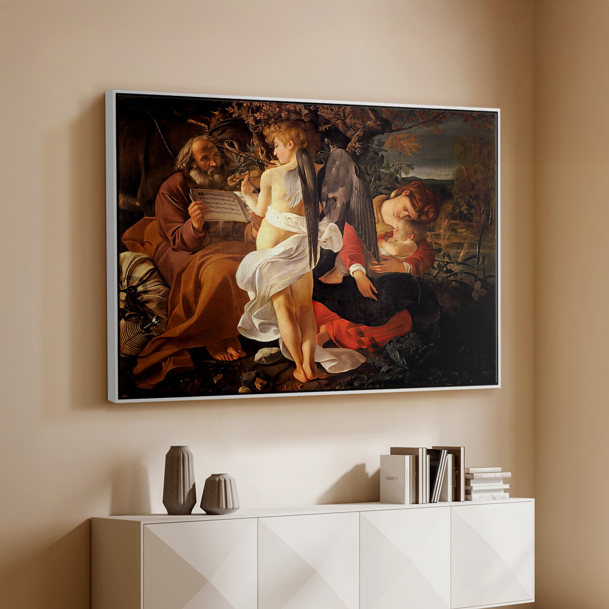 White floater framed canvas of Rest on the Flight into Egypt, c. 1597 by Caravaggio, featuring a biblical scene of Mary, Joseph, and infant resting with angel musician above a console cabinet in a minimalist entryway.