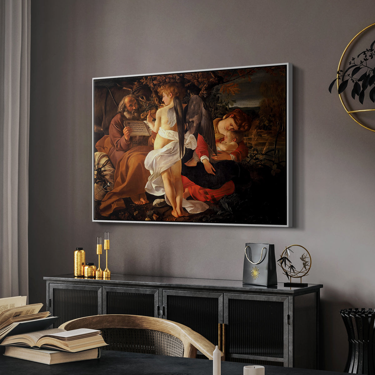Rest on the Flight into Egypt, c. 1597 by Caravaggio in a white floater framed canvas featuring a peaceful religious moment with figures reclining in natural setting, displayed above a desk in a dark home office interior.