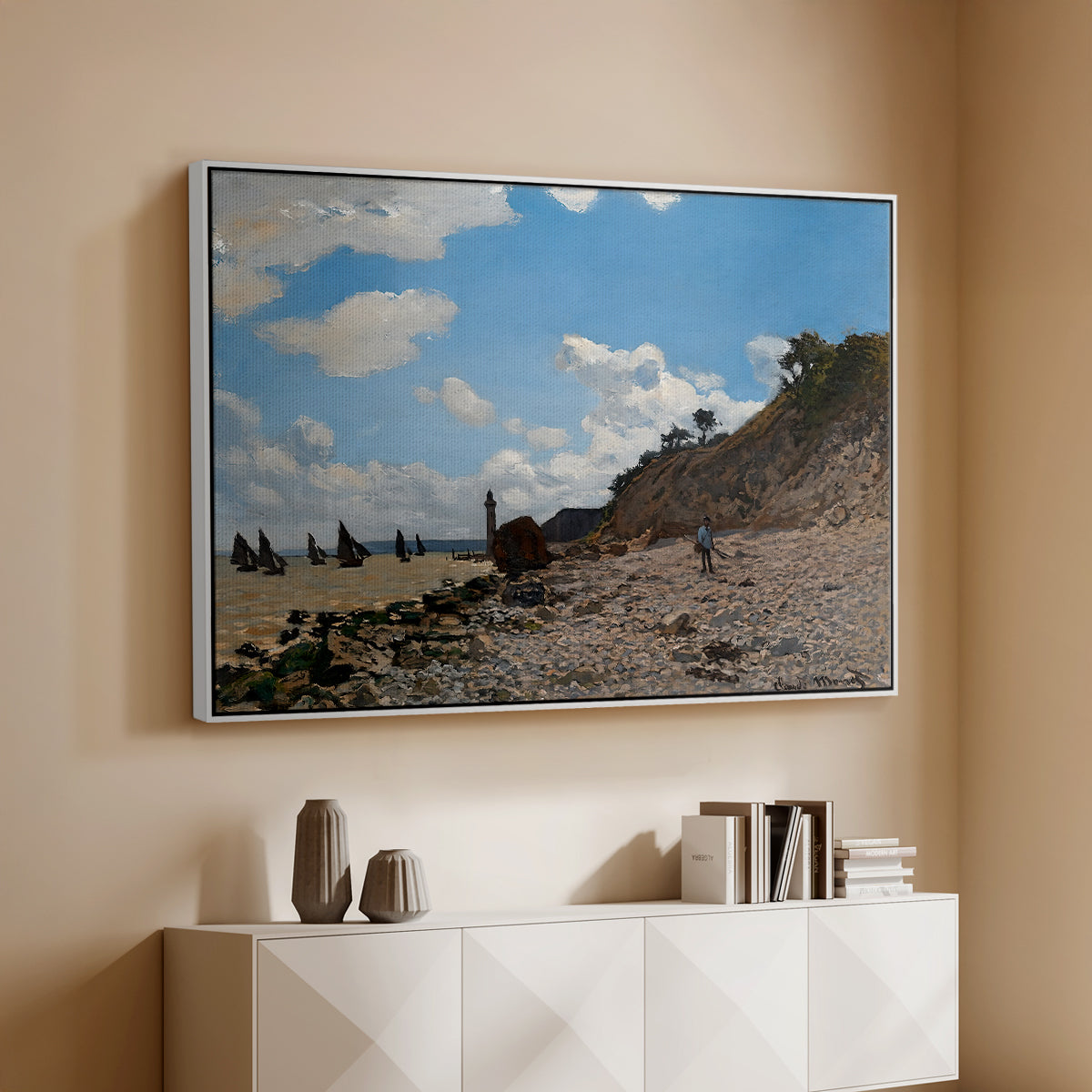 White floater framed canvas of The Beach at Honfleur, 1864 by Claude Monet, featuring an impressionist seaside with people and sailboats under bright sky above a console cabinet in a minimalist entryway.