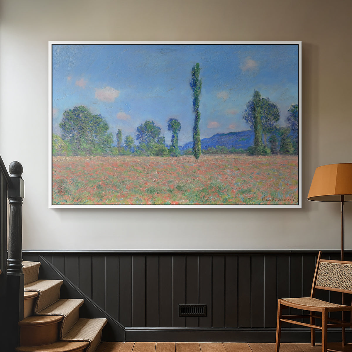 White floater framed canvas featuring a rural field filled with red blossoms beneath open sky, displayed in a hallway near a staircase.