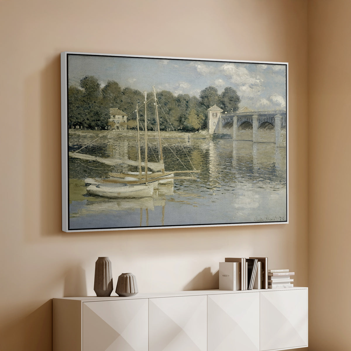 White floater framed canvas of The Bridge at Argenteuil, 1874 by Claude Monet, featuring an impressionist river scene with boats passing beneath bridge above a console cabinet in a minimalist entryway.