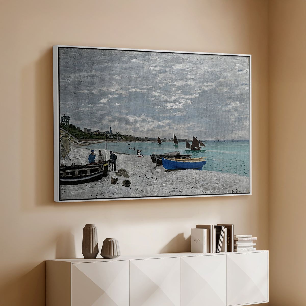 White floater framed canvas of The Beach at Sainte-Adresse, 1867 by Claude Monet, featuring a lively beach scene with people overlooking water and ships above a console cabinet in a minimalist entryway.