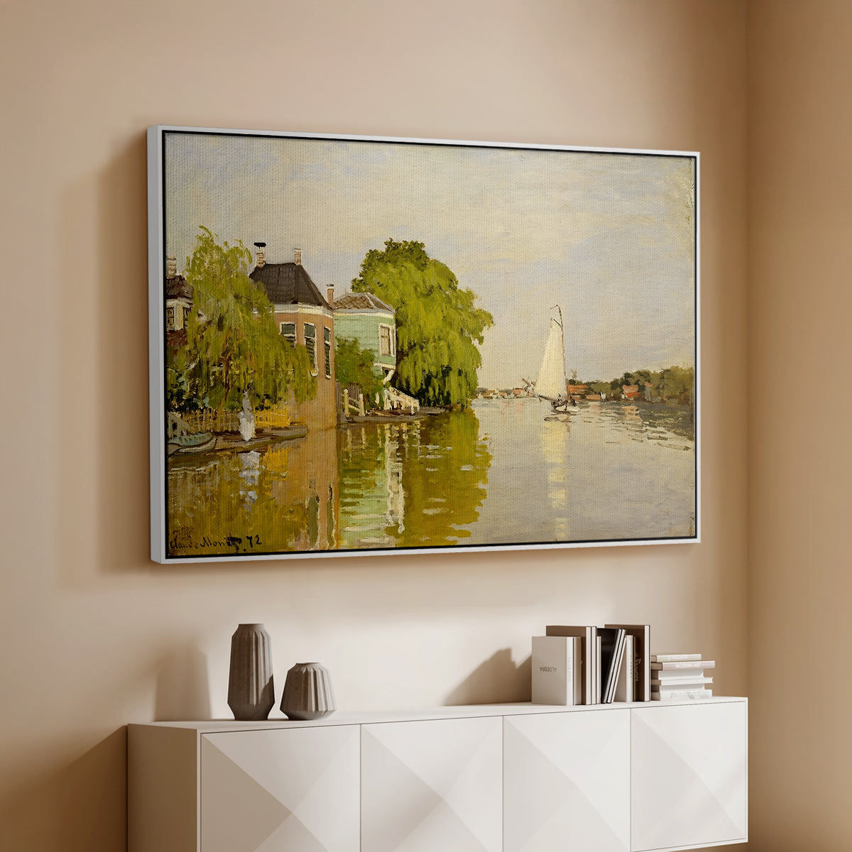 White floater framed canvas of Houses on the Achterzaan, 1871 by Claude Monet, featuring riverside homes with trees and mirrored reflections in water above a console cabinet in a minimalist entryway.