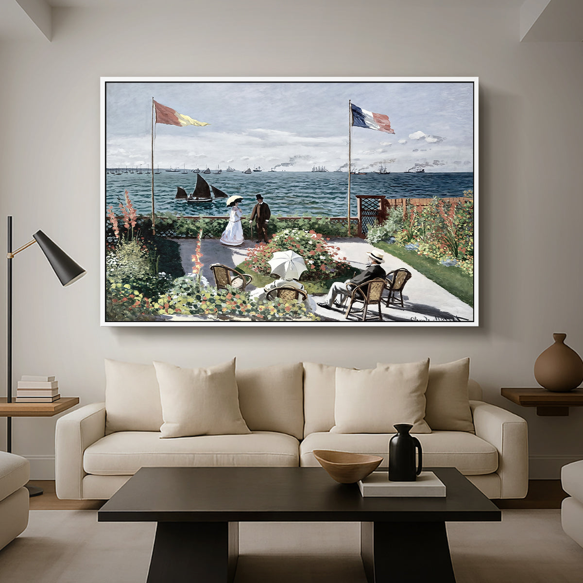 Garden at Sainte-Adresse, 1867 by Claude Monet as a white floater framed canvas featuring a seaside garden with flowers, flags, and figures overlooking the water, displayed above a sofa in a modern living room.