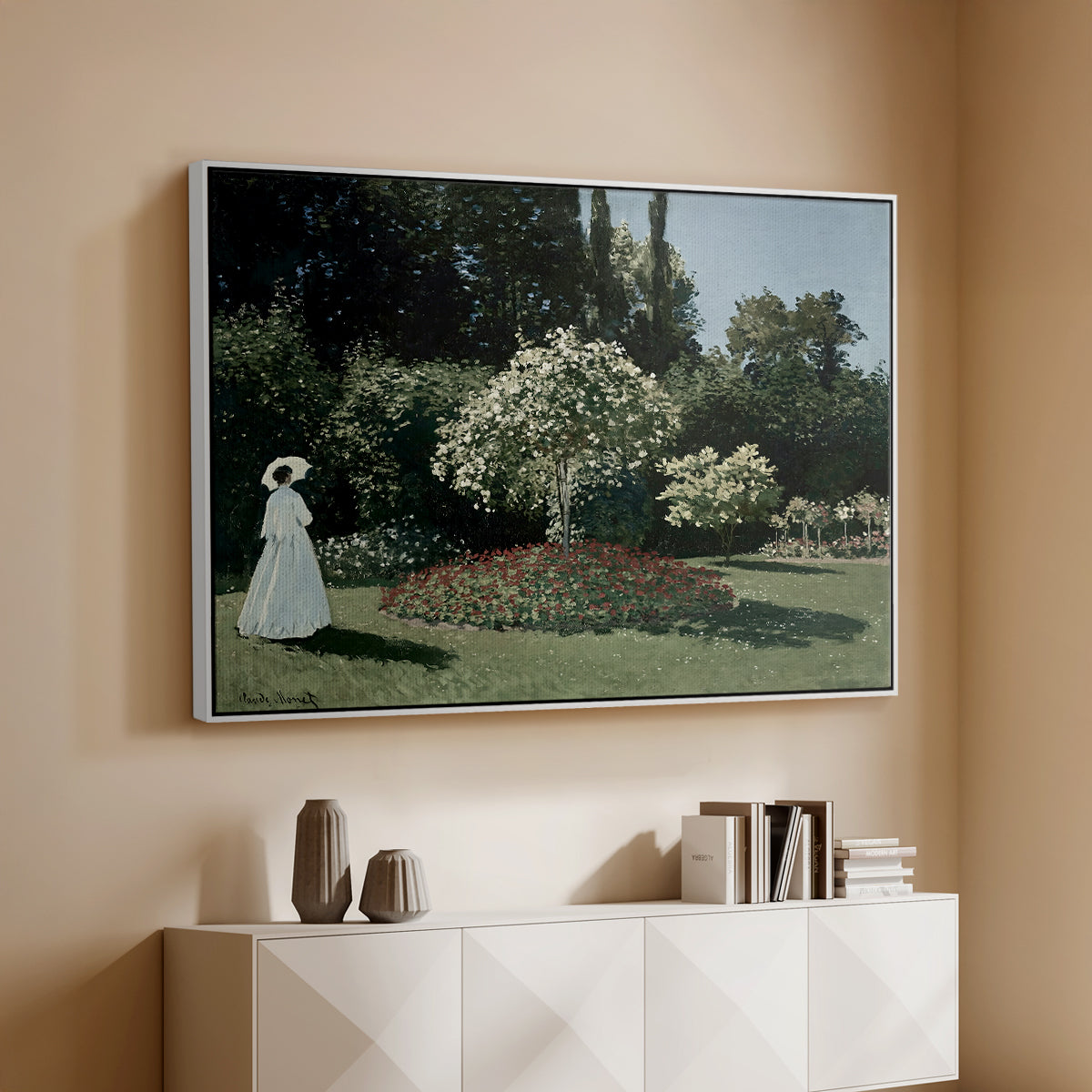 White floater framed canvas of Woman in the Garden, Sainte-Adresse, 1867 by Claude Monet, featuring an impressionist figure in sunlit garden with lush vegetation above a console cabinet in a minimalist entryway.