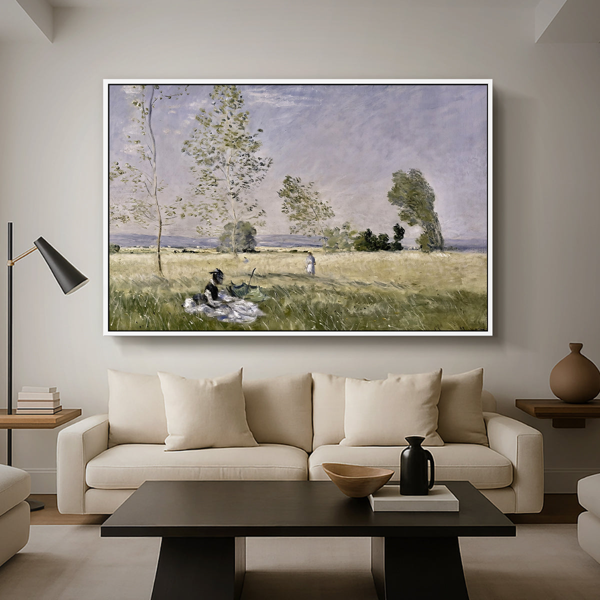 Summer (L'ete), 1874 by Claude Monet as a white floater framed canvas featuring a woman seated in grassy field beneath tree in bright summer landscape, displayed above a sofa in a modern living room.