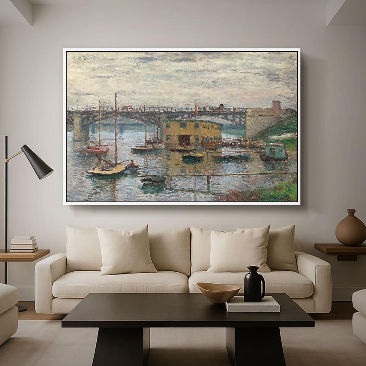 Bridge at Argenteuil on a Gray Day, c. 1876 by Claude Monet as a white floater framed canvas featuring a bridge crossing river under gray sky with muted reflections, displayed above a sofa in a modern living room.
