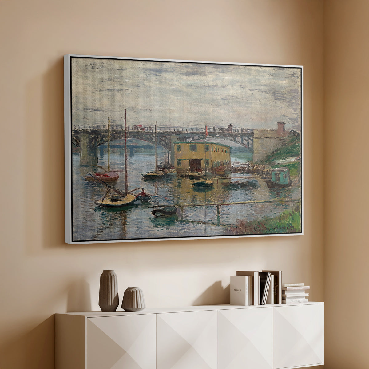 White floater framed canvas of Bridge at Argenteuil on a Gray Day, c. 1876 by Claude Monet, featuring an impressionist riverscape with overcast atmosphere and soft tones above a console cabinet in a minimalist entryway.