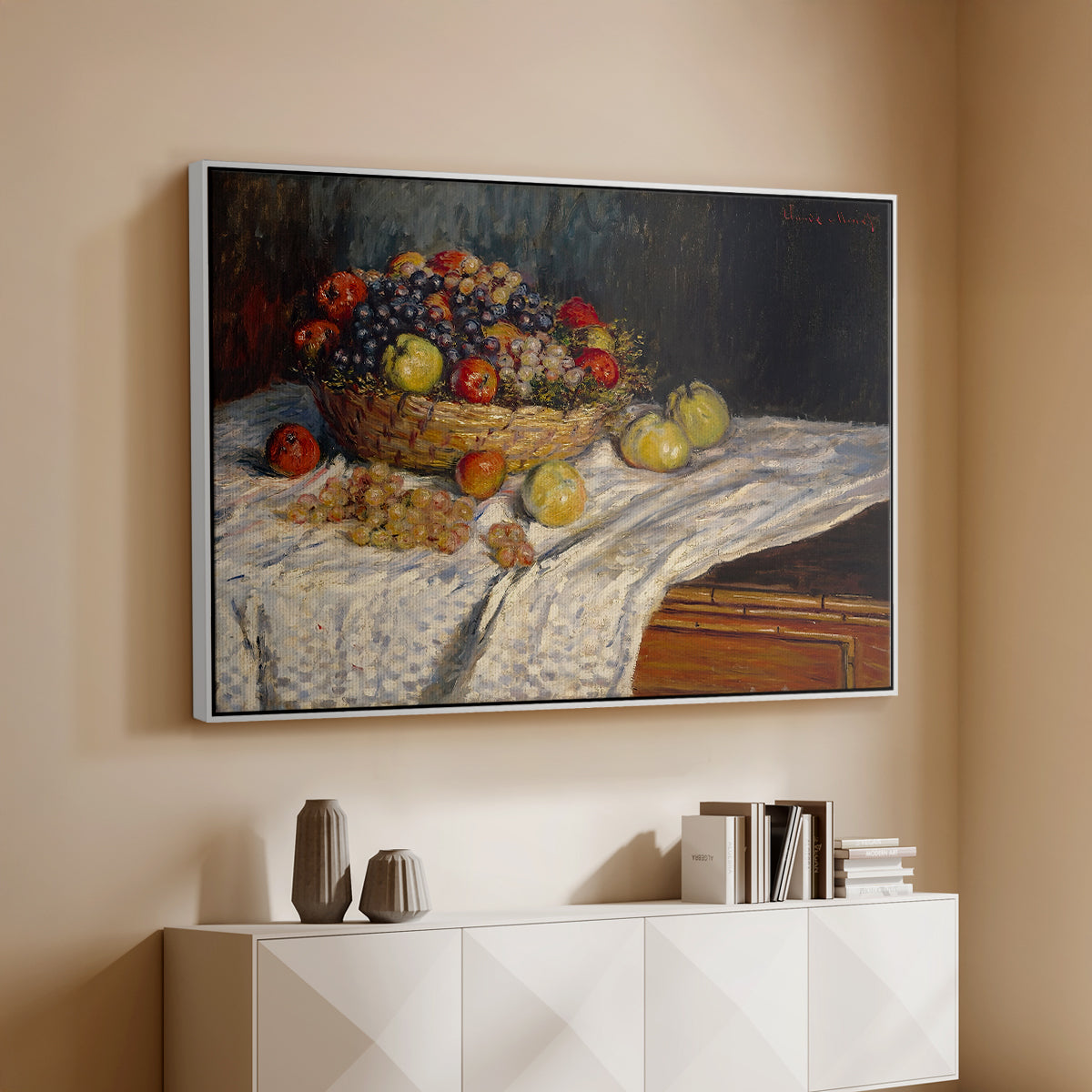 White floater framed canvas of Still Life with Apples and Grapes, 1880 by Claude Monet, featuring an impressionist still life of fruit placed on cloth-covered surface above a console cabinet in a minimalist entryway.