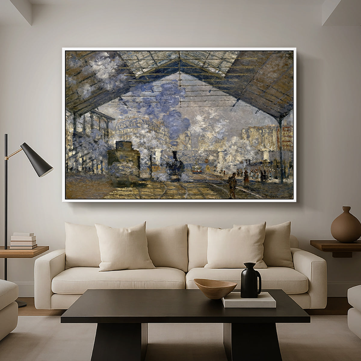 The Gare Saint-Lazare, 1877 by Claude Monet as a white floater framed canvas featuring a train station interior filled with steam and locomotives under iron structure, displayed above a sofa in a modern living room.