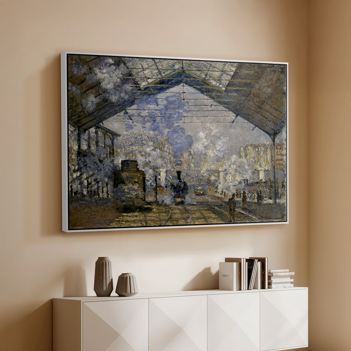White floater framed canvas of The Gare Saint-Lazare, 1877 by Claude Monet, featuring an impressionist scene of trains and smoke inside busy railway station above a console cabinet in a minimalist entryway.
