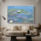 Water Lilies (Nymphéas), 1897-1899 by Claude Monet as a white floater framed canvas featuring floating water lilies on pond with reflections of sky and foliage, displayed above a sofa in a modern living room.