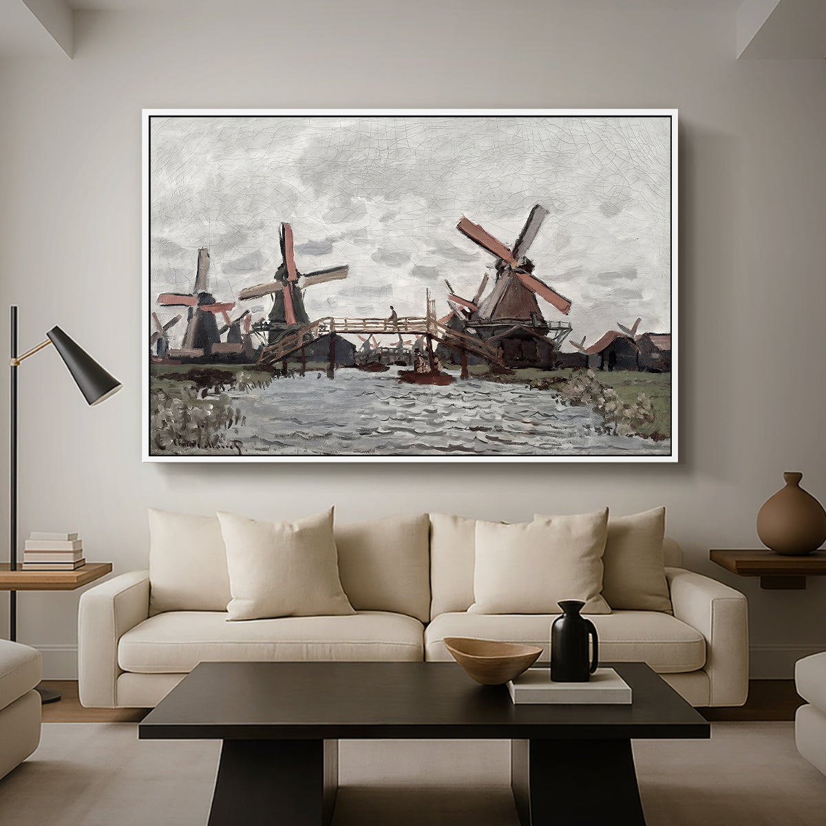 Windmills near Zaandam, 1871 by Claude Monet as a white floater framed canvas featuring windmills standing beside water under open sky in rural landscape, displayed above a sofa in a modern living room.