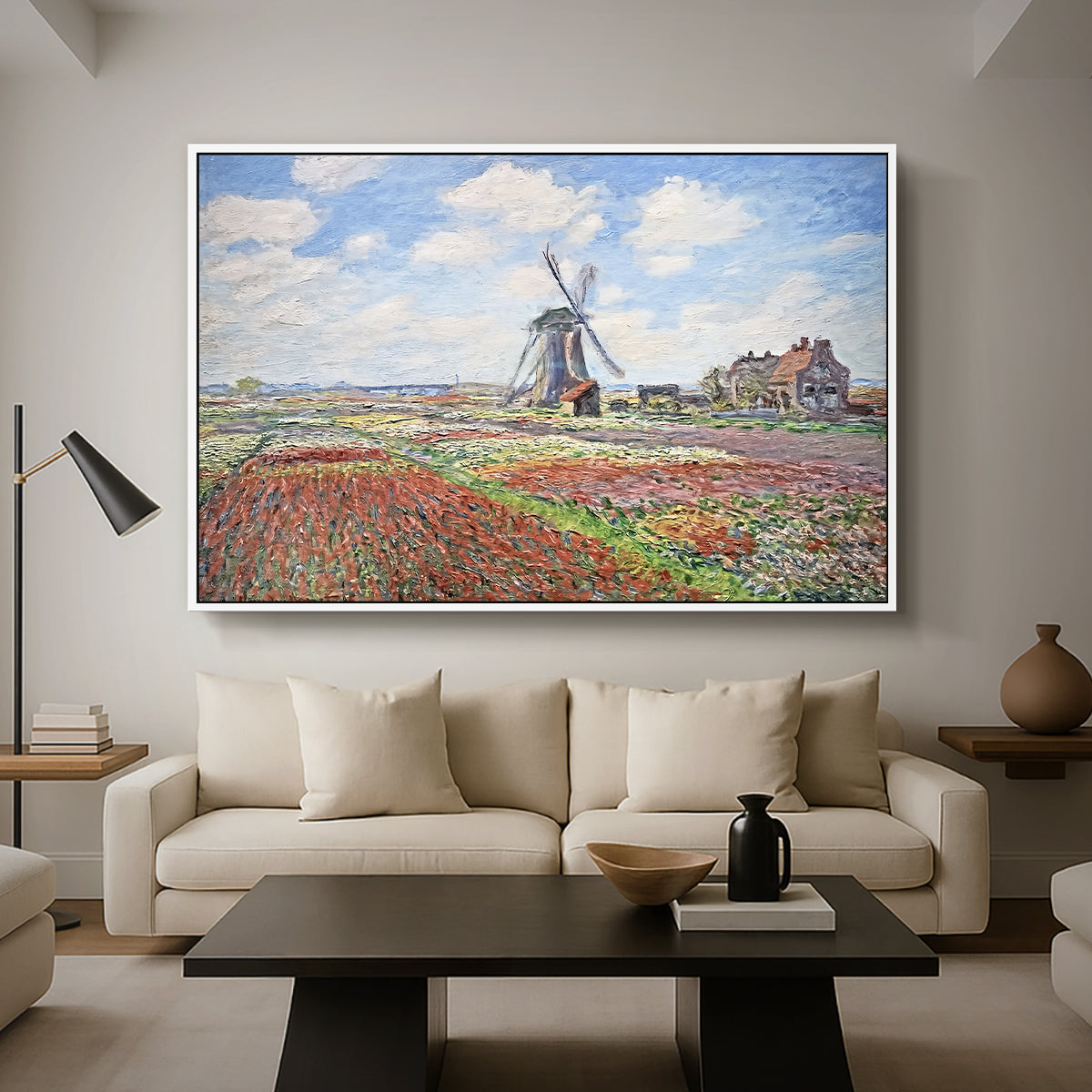 Tulip Fields with the Rijnsburg Windmill, 1886 by Claude Monet as a white floater framed canvas featuring colorful rows of tulip fields leading toward distant windmill, displayed above a sofa in a modern living room.