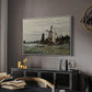 Windmill at Zaandam, 1871 by Claude Monet in a white floater framed canvas featuring a rustic scene with windmill and reflections in water, displayed above a desk in a dark home office interior.