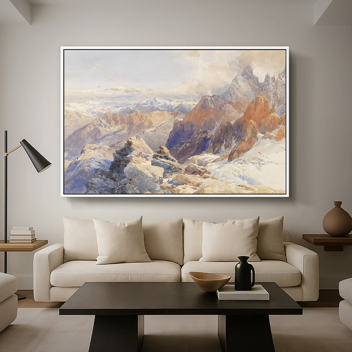 Col du Géant, 1903 by Edward Theodore Compton as a white floater framed canvas featuring a mountain pass with snow-covered peaks and expansive alpine valley, displayed above a sofa in a modern living room.