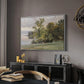 Landscape at Lake Starnberg, 1890 by Edward Theodore Compton in a white floater framed canvas featuring a natural setting with water, trees, and open sky, displayed above a desk in a dark home office interior.