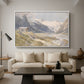 Shepherds (Pasterze), c. 1921 by Edward Theodore Compton as a white floater framed canvas featuring a small group of shepherds in alpine landscape with grazing animals, displayed above a sofa in a modern living room.