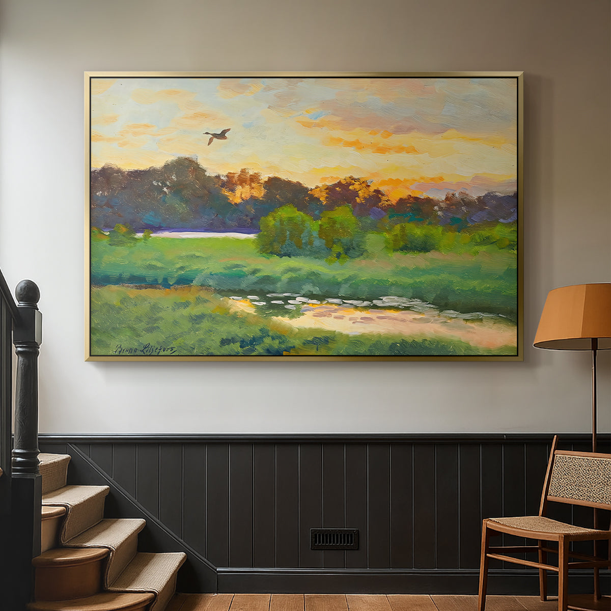 Gold floater framed canvas featuring a lone duck flying over a marsh at golden hour, displayed in a hallway near a staircase.