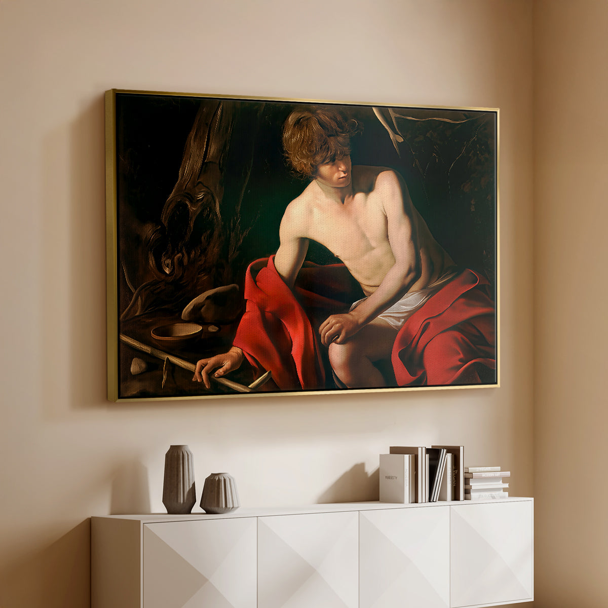 Gold floater framed canvas of Saint John the Baptist in the Wilderness, c. 1603-1604 by Caravaggio, featuring a solitary figure of Saint John resting in natural setting with soft light above a console cabinet in a minimalist entryway.