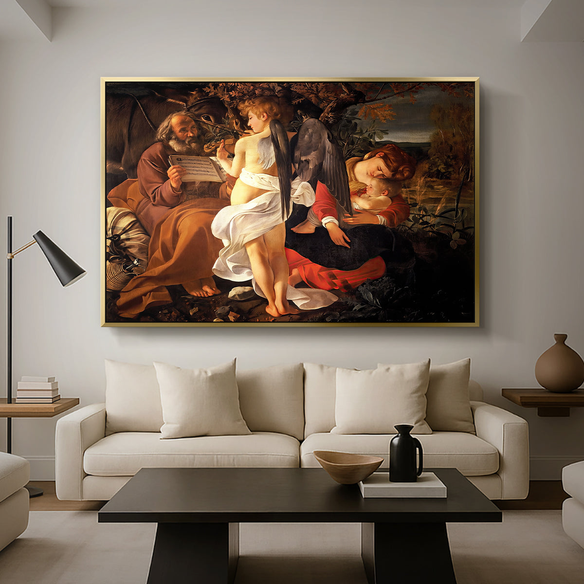 Rest on the Flight into Egypt, c. 1597 by Caravaggio as a gold floater framed canvas featuring the Holy Family resting in landscape with angel playing violin, displayed above a sofa in a modern living room.
