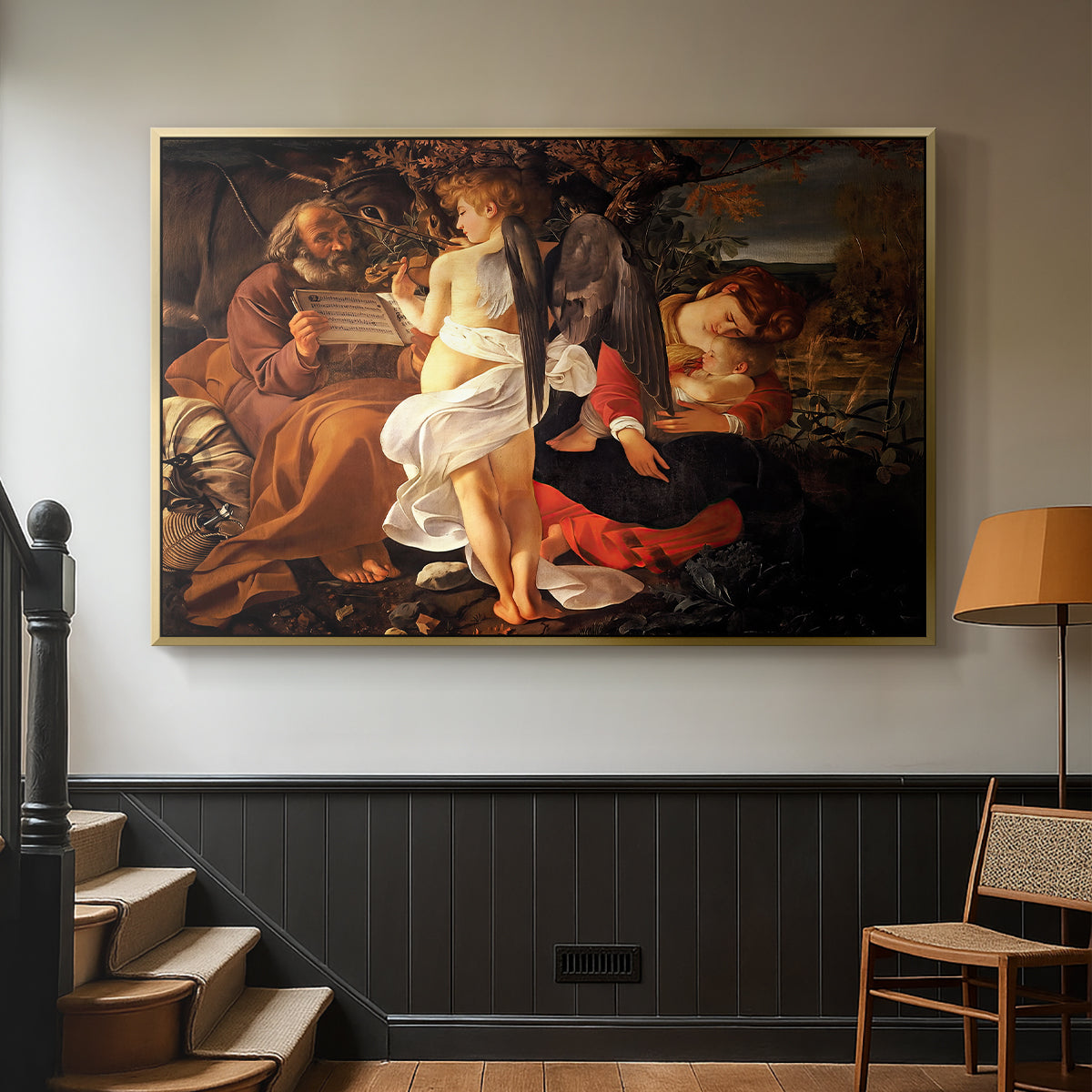 Gold floater framed canvas featuring a Baroque landscape with angel playing music for resting travelers, displayed in a hallway near a staircase.