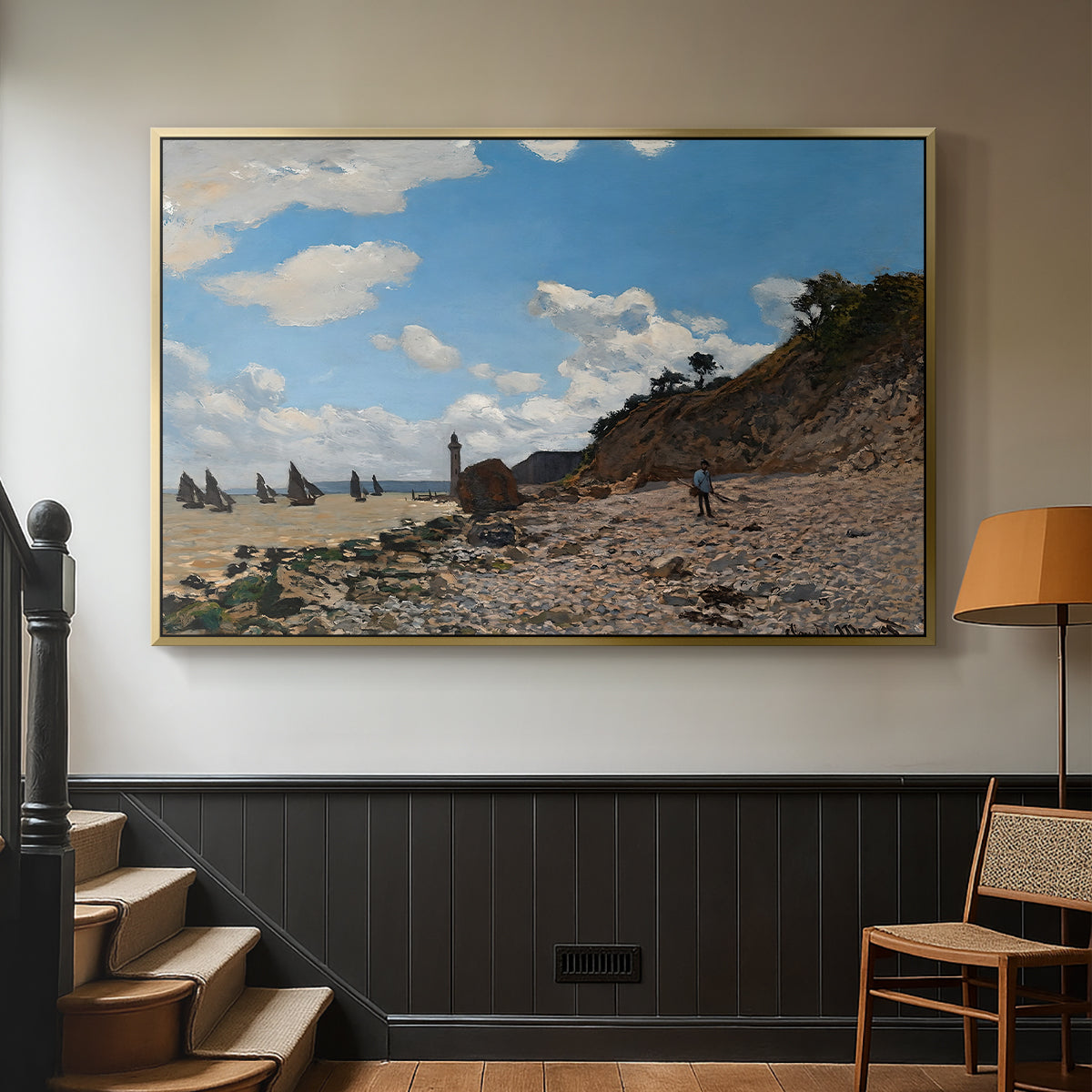 Gold floater framed canvas featuring a coastal landscape with boats and people along shore, displayed in a hallway near a staircase.