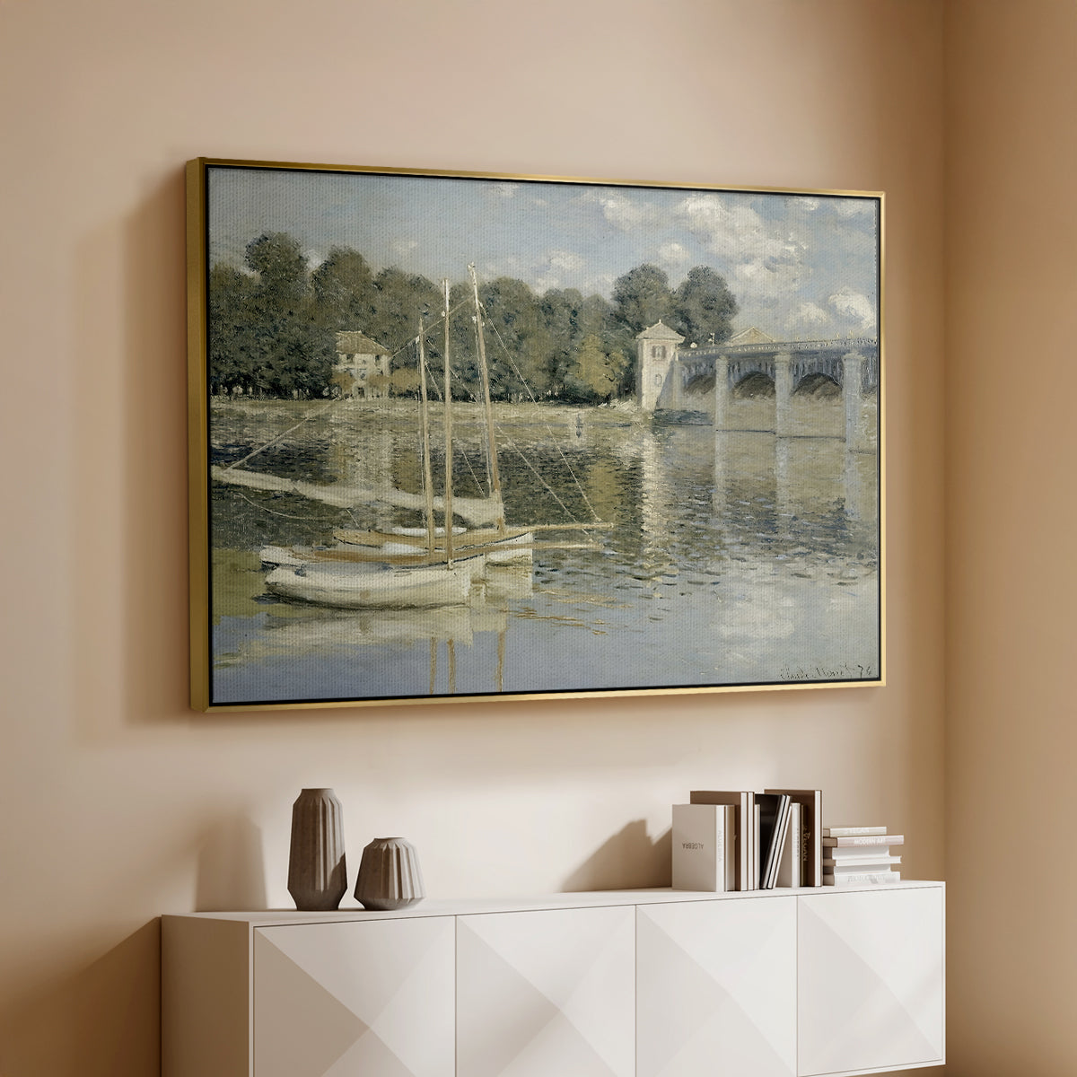 Gold floater framed canvas of The Bridge at Argenteuil, 1874 by Claude Monet, featuring an impressionist river scene with boats passing beneath bridge above a console cabinet in a minimalist entryway.