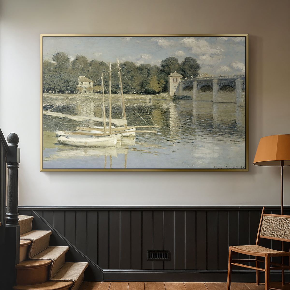 Gold floater framed canvas featuring a riverside view with architecture and nautical activity, displayed in a hallway near a staircase.