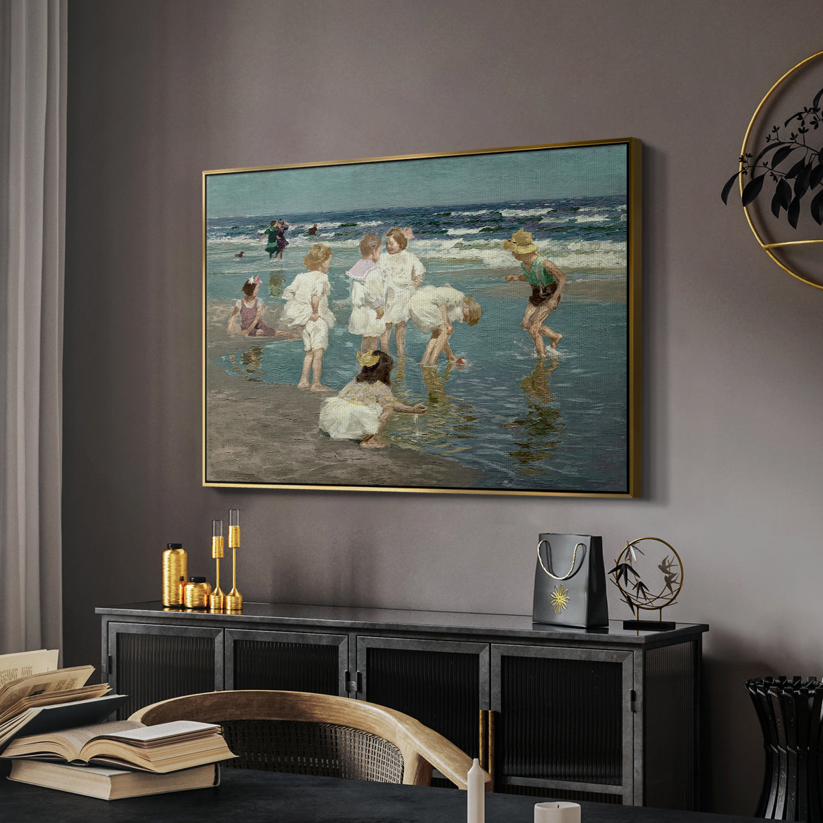 A Holiday, c. 1915 by Edward Henry Potthast in a gold floater framed canvas featuring an impressionist coastal view of families enjoying seaside water, displayed above a desk in a dark home office interior.