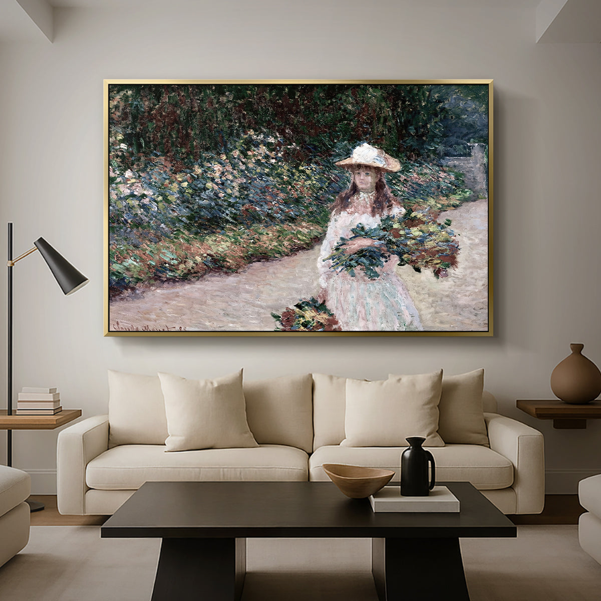 Young Girl in the Garden at Giverny, 1888 by Claude Monet as a gold floater framed canvas featuring a young girl seated in lush garden surrounded by blooming flowers, displayed above a sofa in a modern living room.