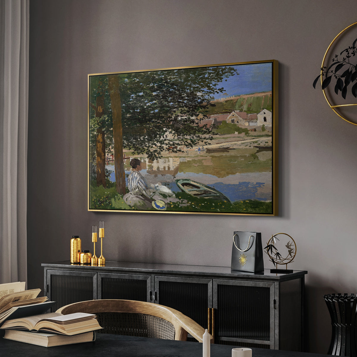 On the Bank of the Seine, Bennecourt, 1868 by Claude Monet in a gold floater framed canvas featuring an impressionist landscape with people relaxing along the Seine, displayed above a desk in a dark home office interior.