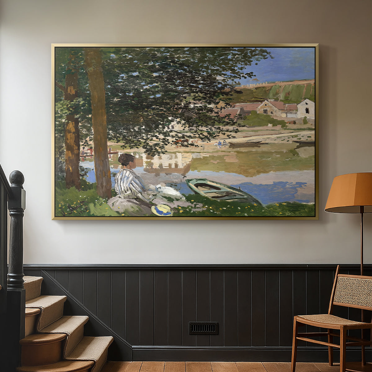 Gold floater framed canvas featuring a quiet outdoor setting with figures near river under foliage, displayed in a hallway near a staircase.