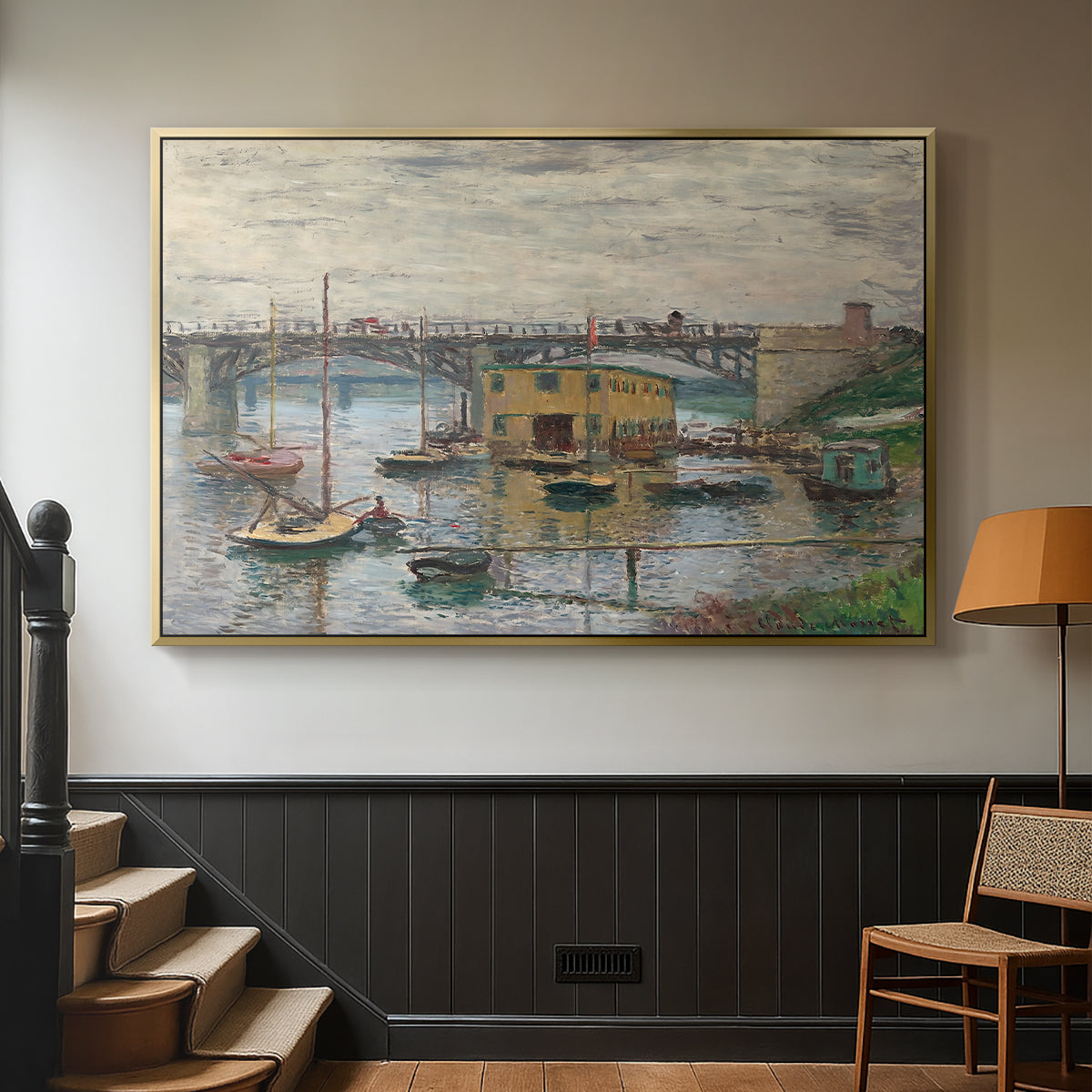 Gold floater framed canvas featuring a subdued urban landscape with structure spanning river, displayed in a hallway near a staircase.