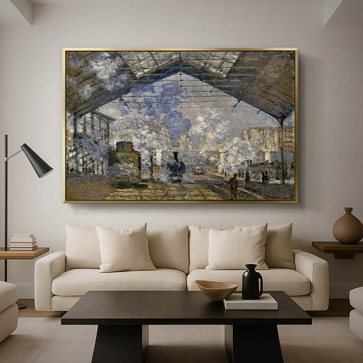 The Gare Saint-Lazare, 1877 by Claude Monet as a gold floater framed canvas featuring a train station interior filled with steam and locomotives under iron structure, displayed above a sofa in a modern living room.