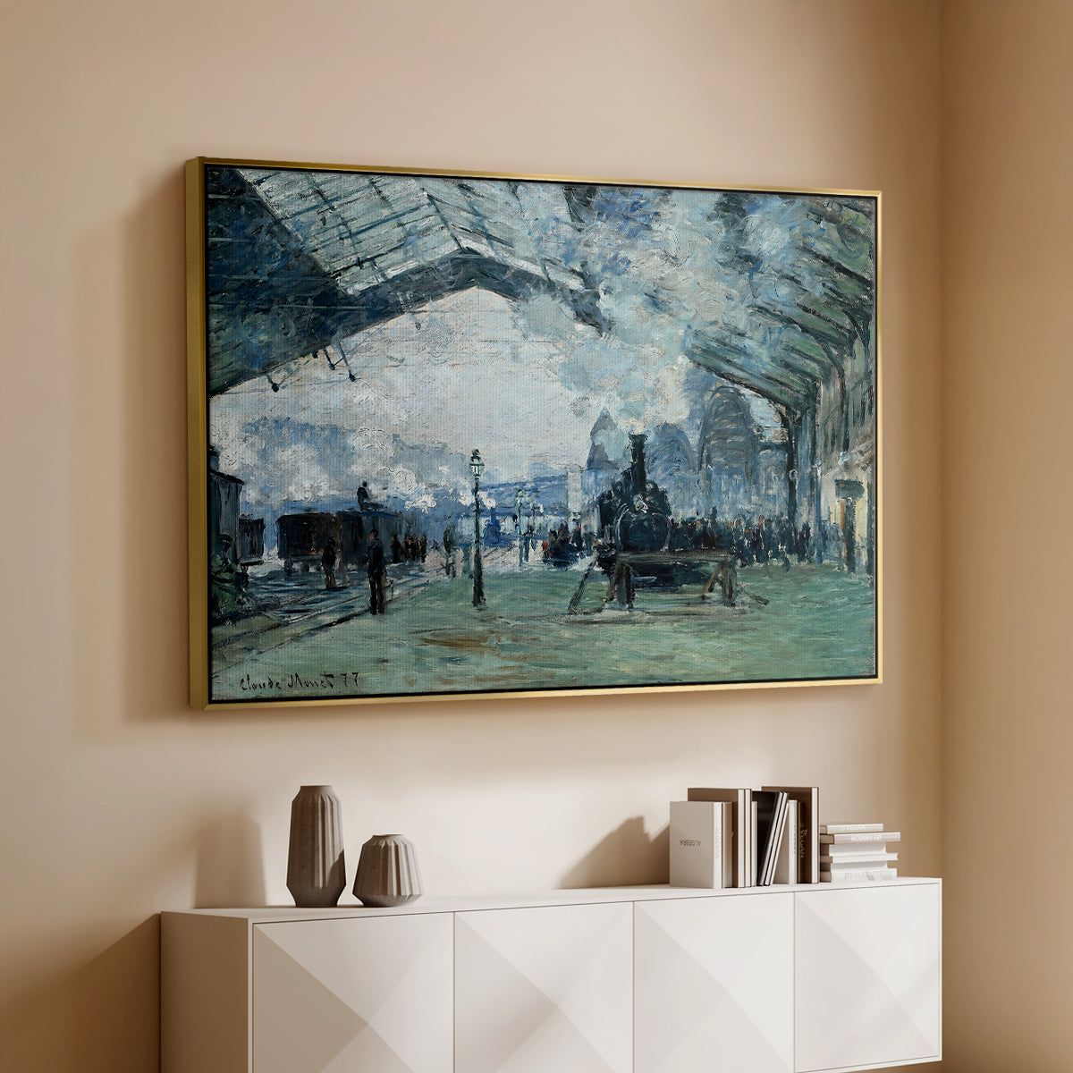 Gold floater framed canvas of The Saint-Lazare Station, 1877 by Claude Monet, featuring an impressionist railway scene with locomotives and haze above a console cabinet in a minimalist entryway.