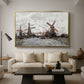 Windmills near Zaandam, 1871 by Claude Monet as a gold floater framed canvas featuring windmills standing beside water under open sky in rural landscape, displayed above a sofa in a modern living room.