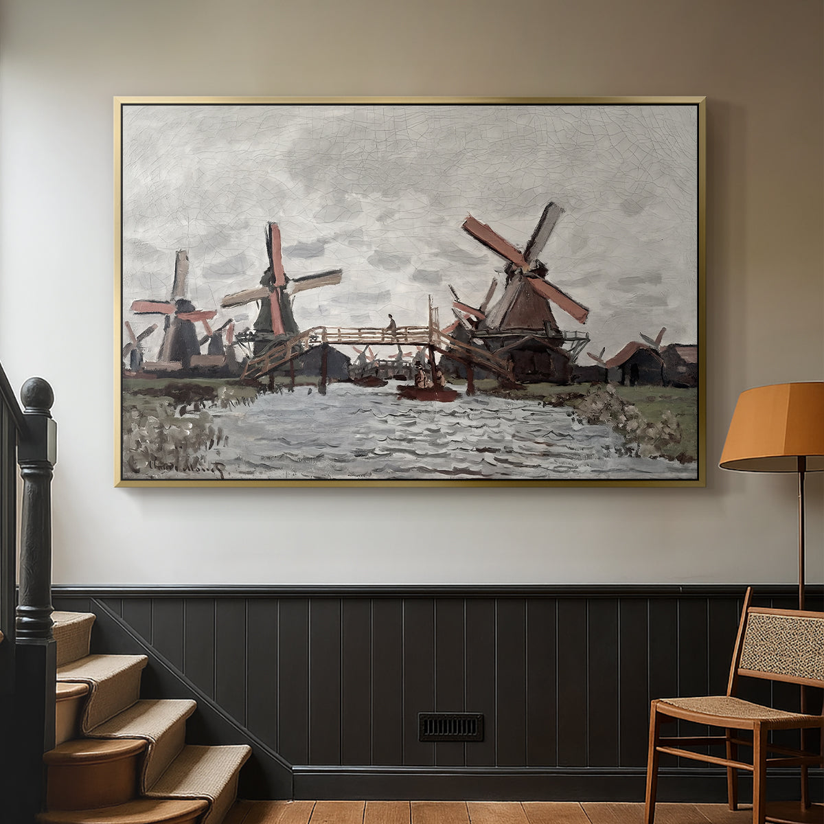 Gold floater framed canvas featuring a landscape featuring windmills and low horizon sky, displayed in a hallway near a staircase.