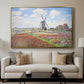 Tulip Fields with the Rijnsburg Windmill, 1886 by Claude Monet displayed in a gold floater framed canvas above a sofa in a clean living room.