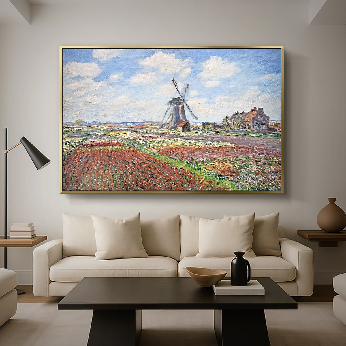 Tulip Fields with the Rijnsburg Windmill, 1886 by Claude Monet as a gold floater framed canvas featuring colorful rows of tulip fields leading toward distant windmill, displayed above a sofa in a modern living room.