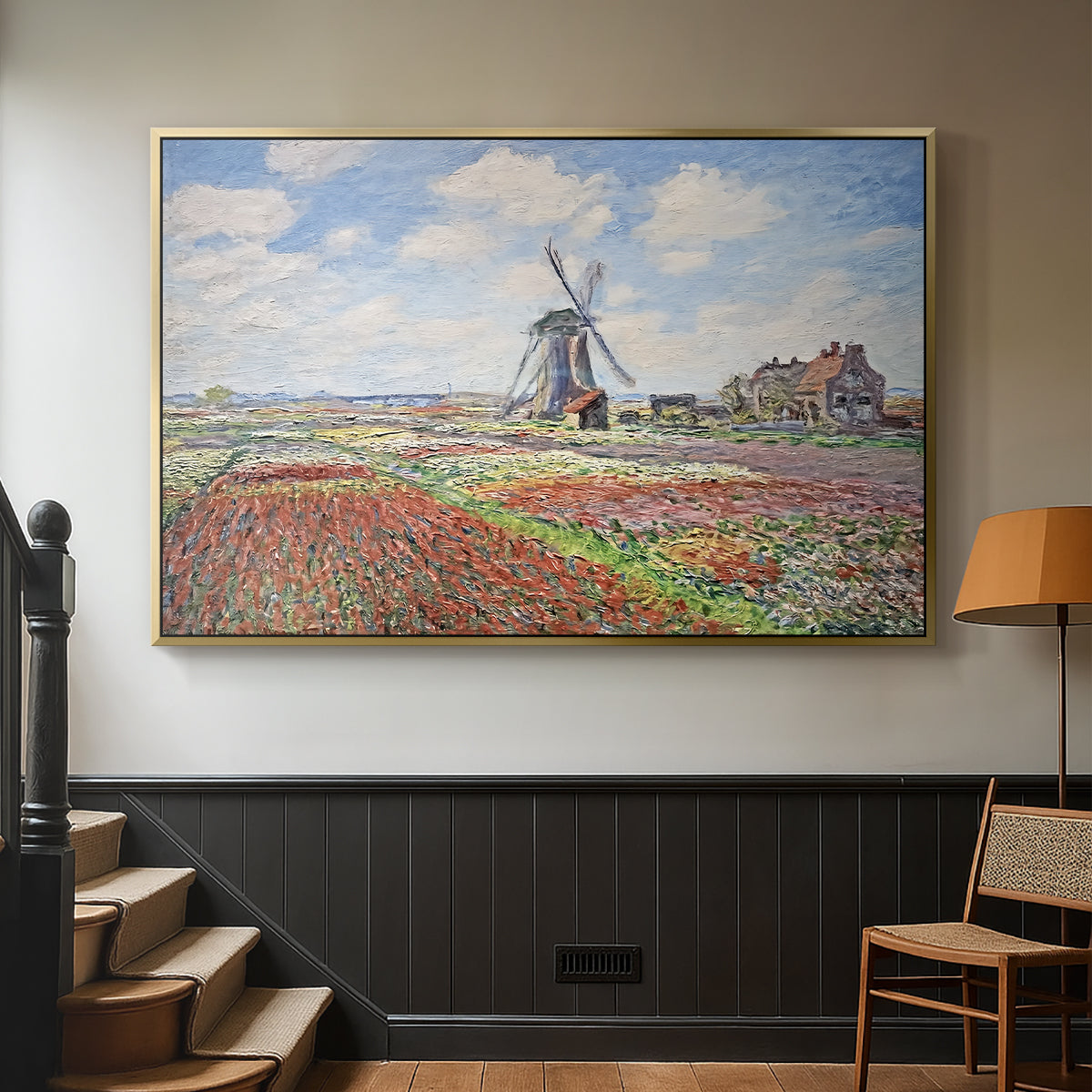 Gold floater framed canvas featuring a rural scene with patterned rows of flowers and windmill, displayed in a hallway near a staircase.
