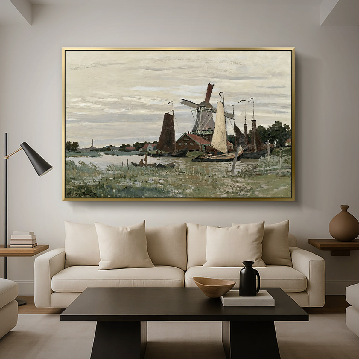Windmill at Zaandam, 1871 by Claude Monet as a gold floater framed canvas featuring a single windmill beside water with surrounding buildings and sky, displayed above a sofa in a modern living room.