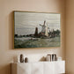Gold floater framed canvas of Windmill at Zaandam, 1871 by Claude Monet, featuring an impressionist depiction of windmill near riverbank above a console cabinet in a minimalist entryway.
