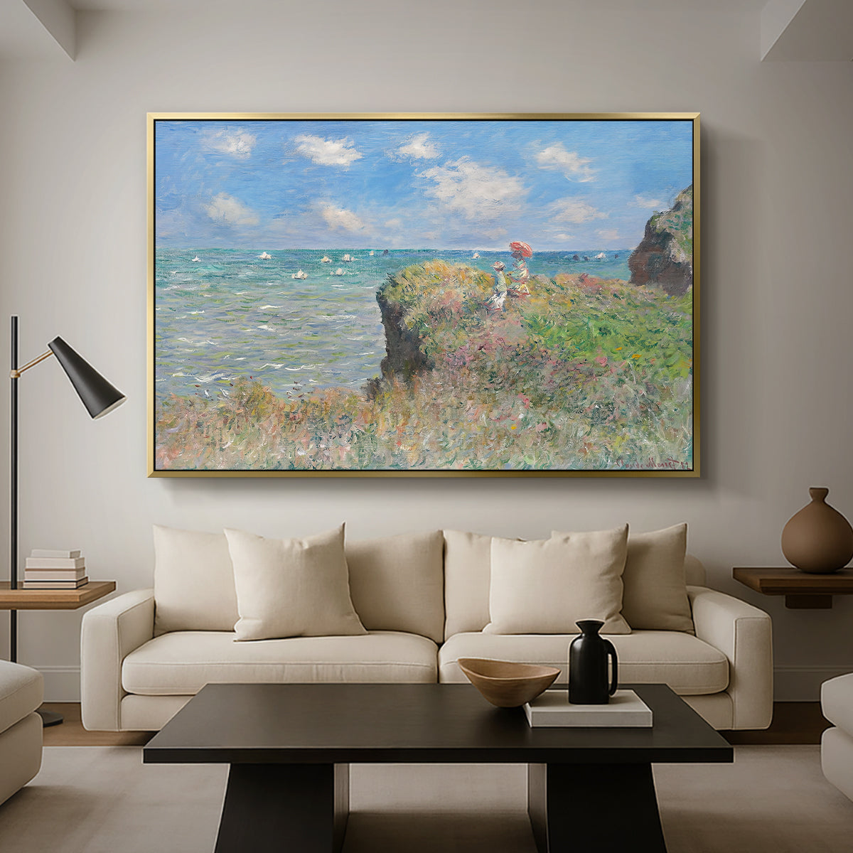 The Cliff Walk at Pourville, 1882 by Claude Monet as a gold floater framed canvas featuring figures walking along coastal cliff path overlooking ocean and sky, displayed above a sofa in a modern living room.