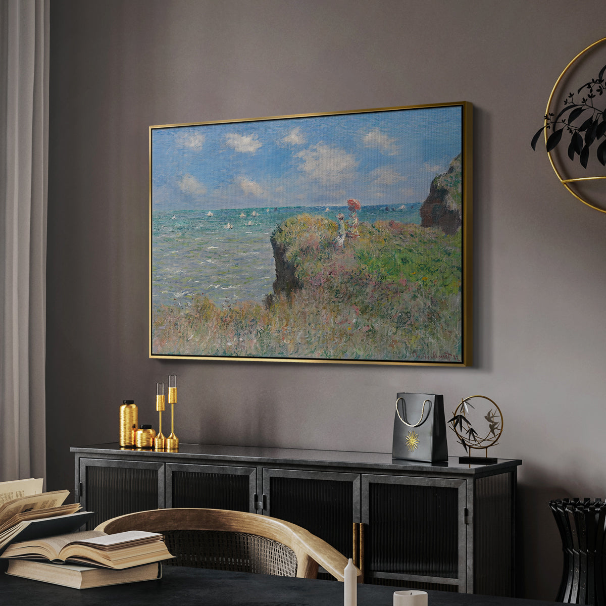 The Cliff Walk at Pourville, 1882 by Claude Monet in a gold floater framed canvas featuring a coastal cliff scene with grass, wind, and expansive sea view, displayed above a desk in a dark home office interior.
