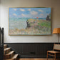 Gold floater framed canvas featuring an elevated shoreline path with figures and bright sky, displayed in a hallway near a staircase.
