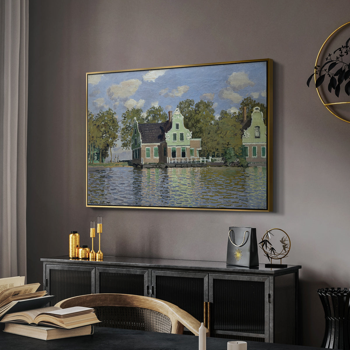 Houses on the Zaan River at Zaandam, 1871 by Claude Monet in a gold floater framed canvas featuring a peaceful canal scene with houses mirrored in water, displayed above a desk in a dark home office interior.