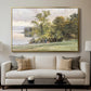 Landscape at Lake Starnberg, 1890 by Edward Theodore Compton displayed in a gold floater framed canvas above a sofa in a clean living room.
