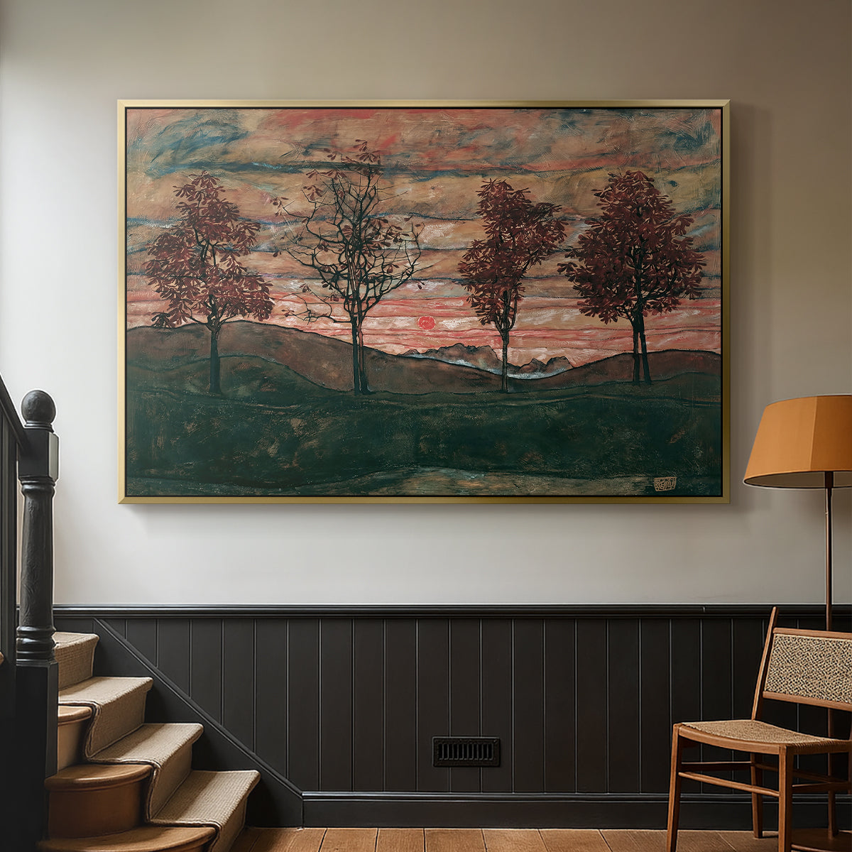 Gold floater framed canvas featuring an expressionist landscape featuring isolated trees in field, displayed in a hallway near a staircase.
