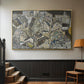 Gold floater framed canvas featuring a stylized urban composition with geometric structures and muted tones, displayed in a hallway near a staircase.